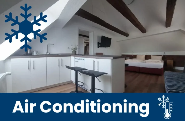 Apartment with sloped ceiling, an open kitchen, and a view of the bed—with a note about the air conditioner