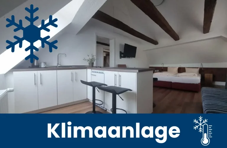 Apartment mit Dachschräge mit offener Küche und Blick auf das Bett - mit Hinweis auf Klimaanlge