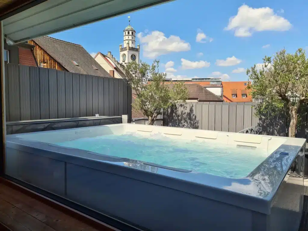 Blick durch eine Scheibe auf einen 8-Personen Whirlpool auf einer Dachterrasse