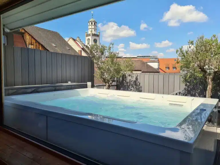 Blick durch eine Scheibe auf einen 8-Personen Whirlpool auf einer Dachterrasse