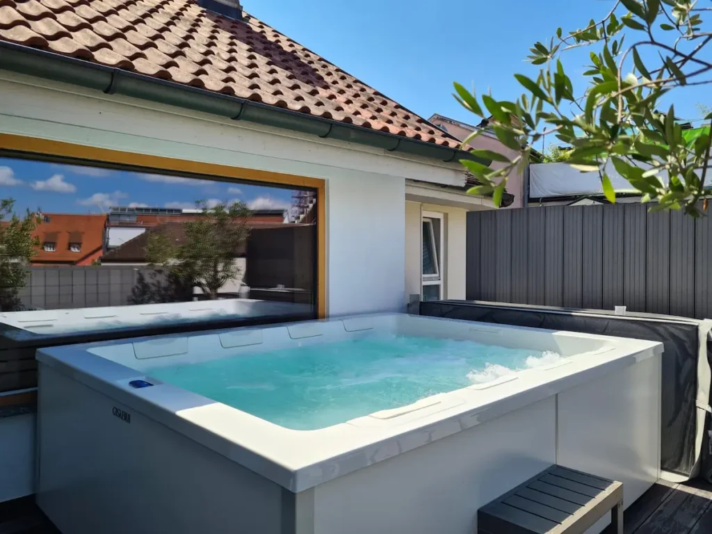 Großer Whirlpool auf einer Dachterrasse vor einem großem Saunafenster